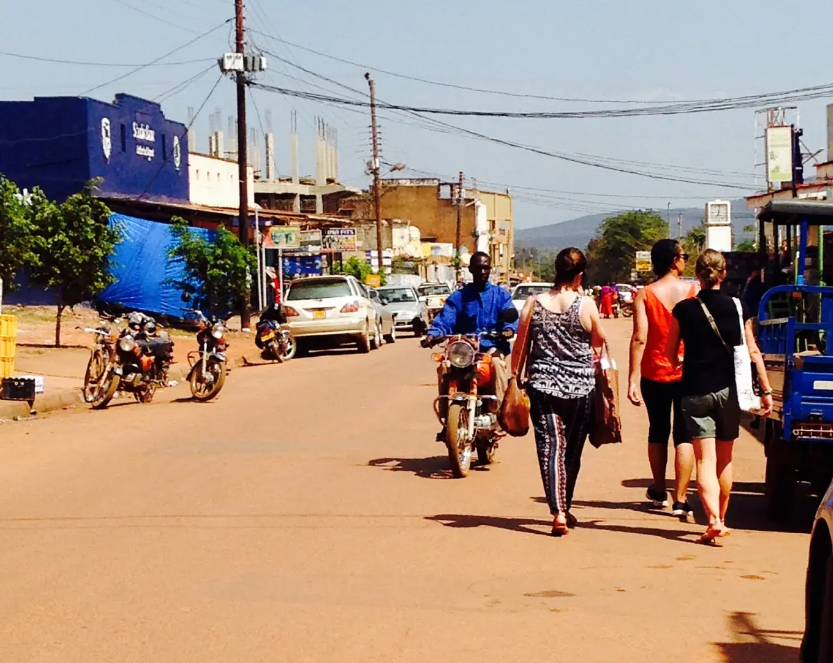 Eine belebte Sandstraße in Masindi mit Motorrädern und Läden