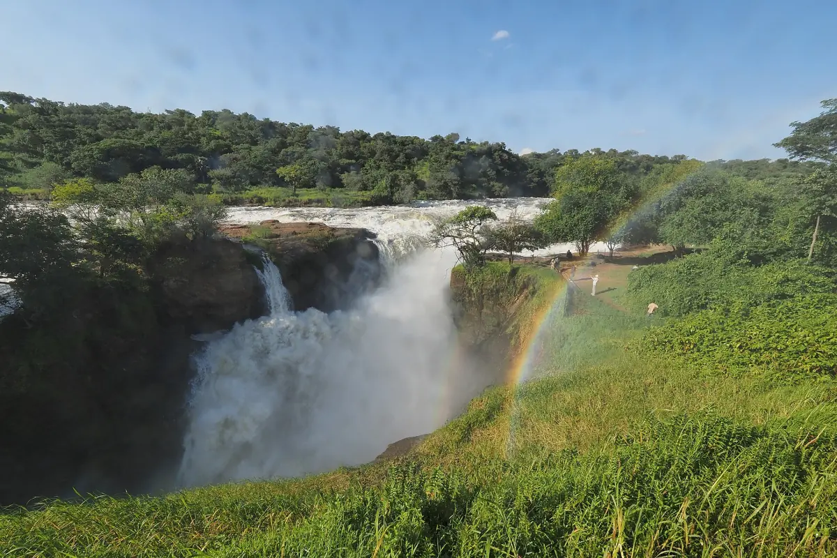 Die Murchison Falls stürzen in die Schlucht, über dem grünen Hang steht ein Regenbogen