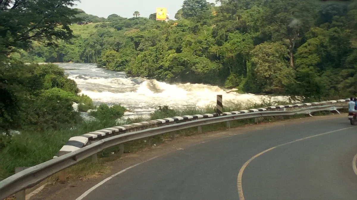 Eine Straße führt in der Kurve an weißen Stromschnellen des Nils bei Karuma vorbei
